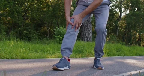 Man massaging leg suffering from knee injury after sport running exercises in Stock Footage 311932643