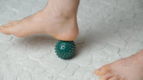 Man massaging myofascial trigger points on foot with green spiky ball Stockbeeldmateriaal 336264901