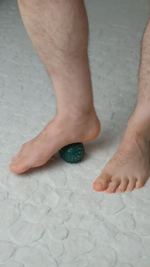 Man massaging myofascial trigger points on foot with green spiky ball Stockbeeldmateriaal 336265208