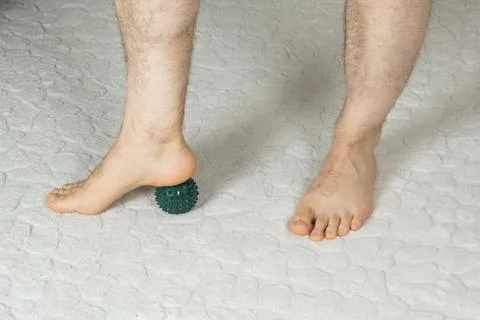 Man massaging myofascial trigger points on foot with green spiky ball Stock Photos