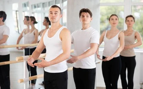 Man mastering first ballet position at barre at group class Stock Photos