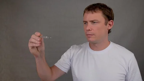 Man measures body temperature looks at a thermometer and puts a mask on his face Stock Footage 128136151