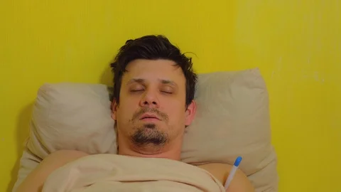 Man measures body temperature using thermometer and puts wet towel on forehead. Stock Footage 128959308