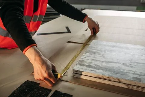 A man measures cardboard with a ruler to create product packaging. Stock Photos