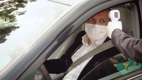 Man measures a driver's body temperature with infrared thermometer Stock Footage 128558135