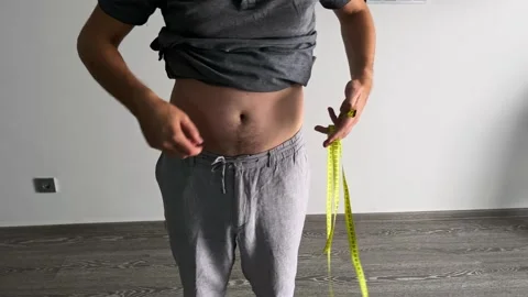 A man measures his abdominal volume with a measuring tape. Stock Footage 283924181