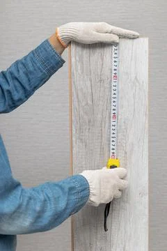 A man measures the length of a board with a tape measure Stock Photos