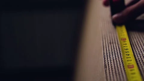 A man measures the length of a stack of cardboard Stock Footage 142623872