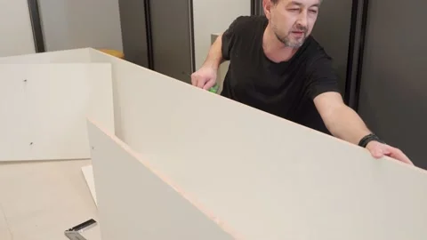 A man measures with a tape measure while assembling furniture. Video stock 198028389