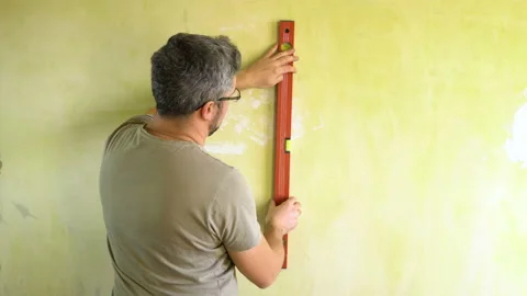 A man measures a wall with a level 4K Video stock 124626956