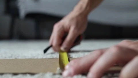 Man measures the width of a sheet of cardboard with a tape measure. Stock Footage 280306575