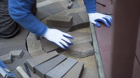 Man measuring and marking bricks for a decorative two tone paver pattern in Stock Footage 81996779