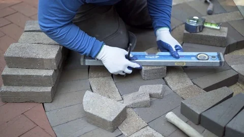Man measuring and marking bricks for a decorative two tone paver pattern in Stock Footage 82073268