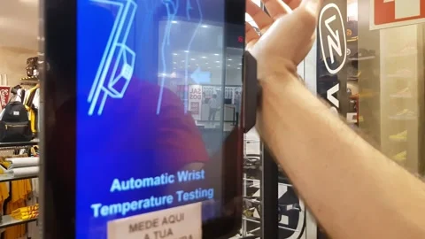 Man measuring body temperature on a machine before entering a store Stock Footage 142530528