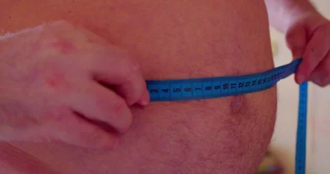 Man measuring his waistline using a tape measure. Vídeo Stock 328527564