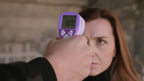 Man measuring the temperature with a contactless thermometer to a young woman. Stock Footage 127969990