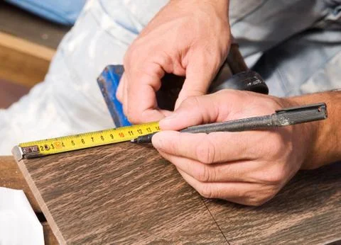 Man measuring a tile piece with a marker Stock Photos