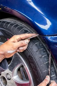 Man mechanic installing the front bumper with his hands of a blue car exterio Stock Photos