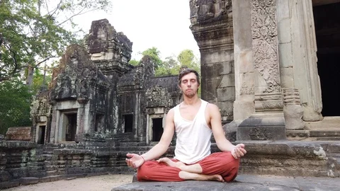 A man meditates on the background of a Small Hindu temple Chau SAI Tevoda  Stock Footage 106494396