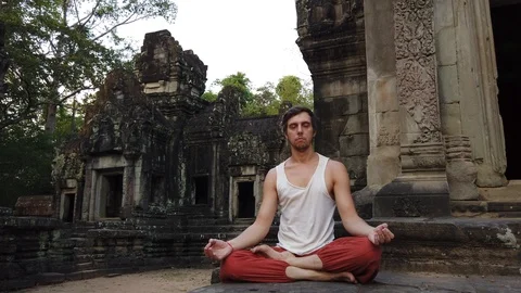 A man meditates on the background of a Small Hindu temple Chau SAI Tevoda Stock Footage 106494451