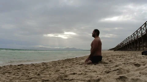 Man meditates on beach Stock Footage 43384070