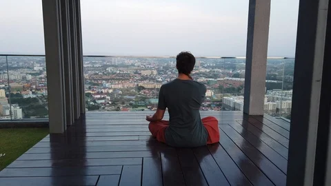 A man meditates being on the view platform on the background of the city.  Stock Footage 104949900