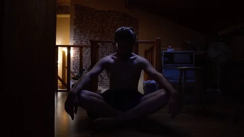 Man meditates in a dark room - 4K Stock Footage