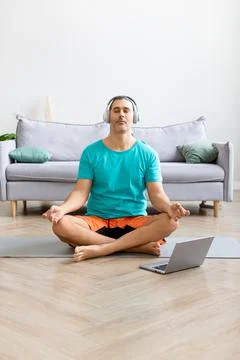 Man meditates at home - using from the internet to monitor the workout. He 写真素材