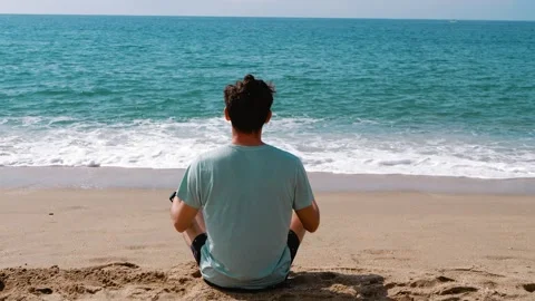 A man meditates on the sand against the backdrop of the sea. Knowing yourself Stock Footage 271197928