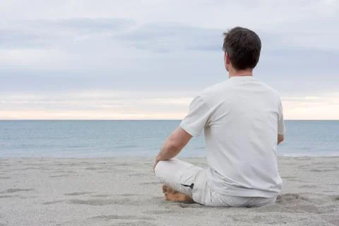 Man meditating on beach Фото