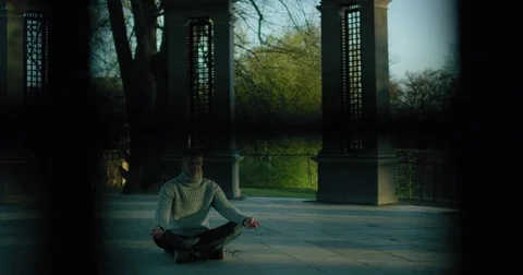 Man meditating, camera slides outside window Stock Footage 77543252