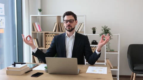 Man meditating at computer desk practicing mindfulness in modern office setting Stock Footage 307993809