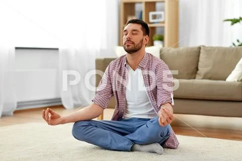 Man meditating in lotus pose at home Stock Photos
