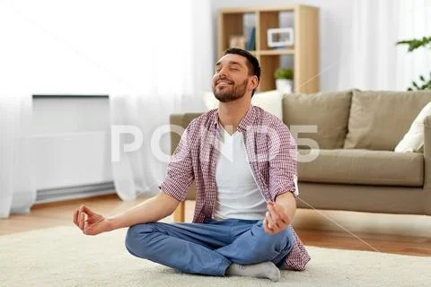 Man meditating in lotus pose at home Stock Photos