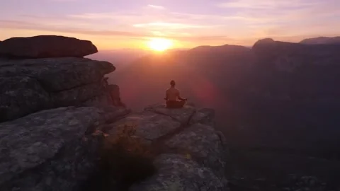 A man meditating on a mountain cliff Stock Footage 312686694