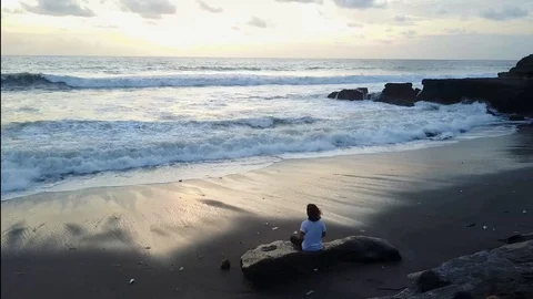 Man Meditating at the Ocean at Sunset on a Beach in Bali Indonesia Stock Footage 102279581