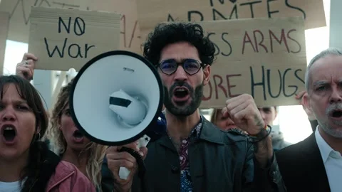 Man with megaphone in a protest with diverse ages group of activist people who Stock Footage 275861991