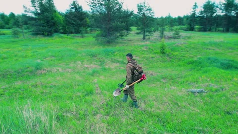 A man with a metal detector in the forest is looking for metal in the ground. Video stock 310960988