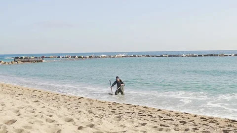 A man with a metal detector is looking for valuable things on the beach Stock Footage 101269389