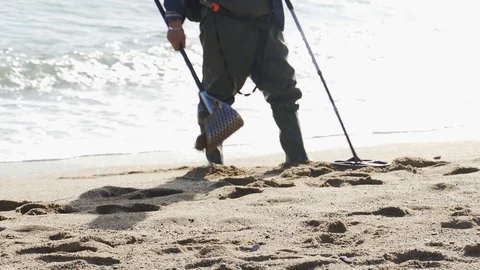A man with a metal detector is looking for valuable things on the beach Stock Footage 101269467