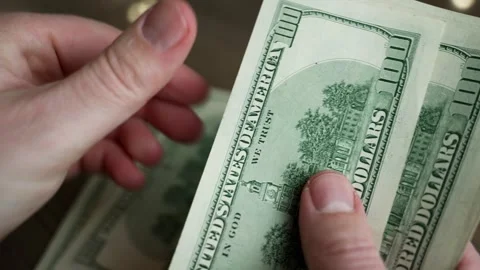 Man meticulously counting a stack of one hundred dollar bills Stock Footage 299200433