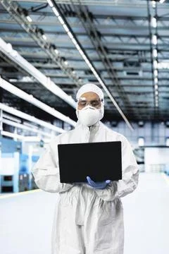 Man in microchip factory testing silicon wafer batches with laptop Stock Photos