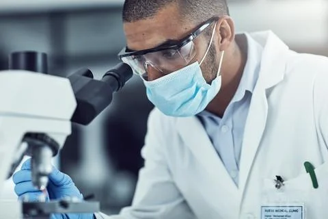 Man, microscope and science at lab with face mask, ppe and perspective for mpox Foto stock