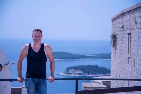 Man, mid 40's,  leans on railing looking at camera Over looking the harbour a Stock Photos