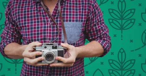 Man mid section with camera against green nature pattern Stock Photos