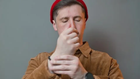 A man of middle age adjusts his wrist while wearing a red beanie and a brown Видео 337643331