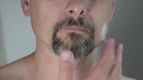 A man of middle ages smears his face with aftershave cream, close-up, 4K Stock Footage 135882815