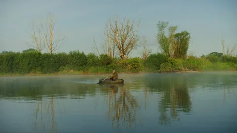 A man in the middle of the lake in a boat while searching for a fishing spot Stock Footage 219777827