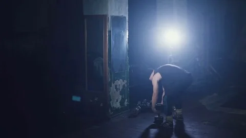 A man at a mirror raises a dumbbell. A dark gym with a blue backlight Stock Footage 73873299