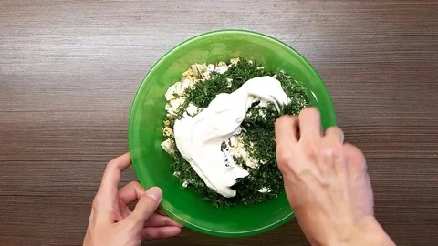 A man mixes boiled eggs with dill greens. The view from the top. Stock Footage 128839050